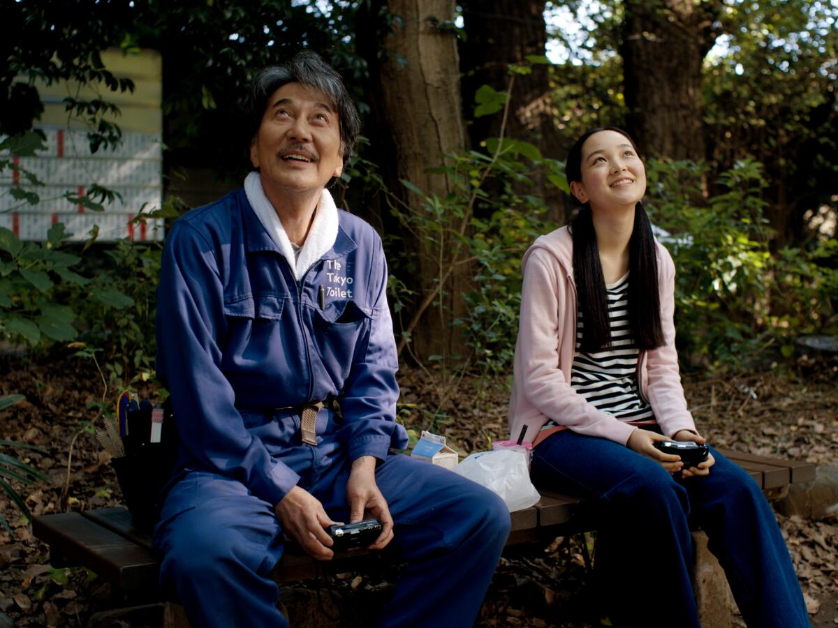 A man and young woman sit together on a park bench in "Perfect Days"