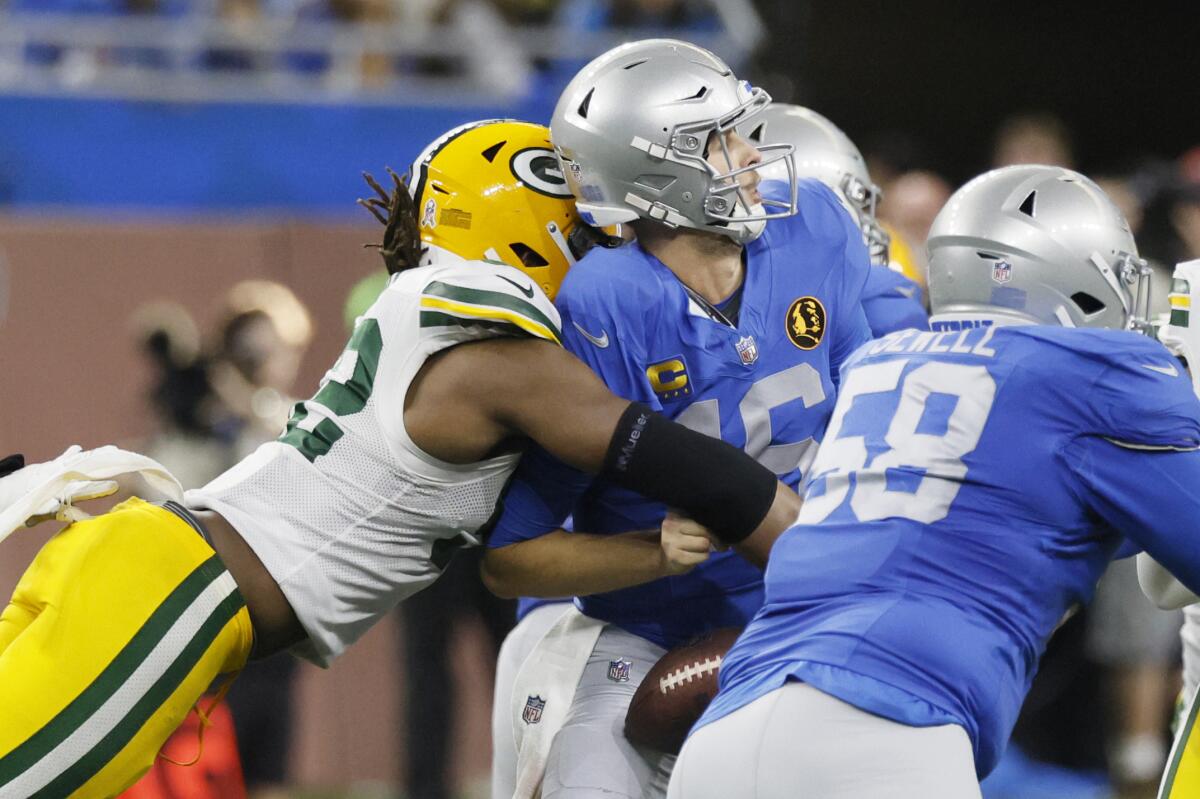 A Green Bay Packers player strips the ball from a Detroit Lions player