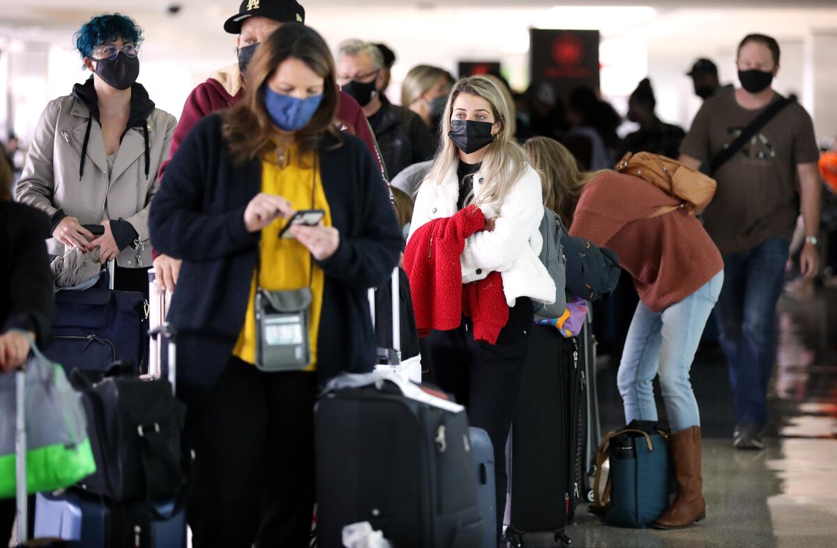 Travelers wait in line to check in for flights at an airport