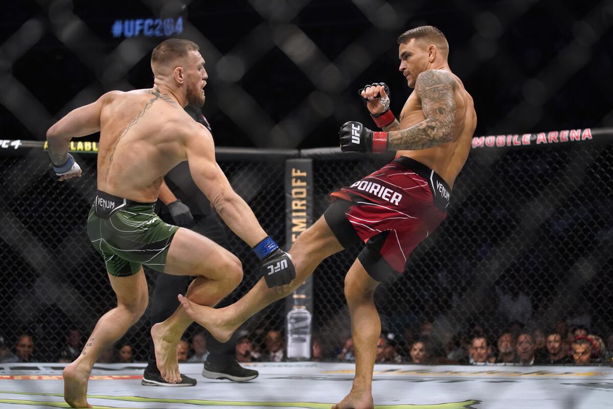 Dustin Poirier, right, kicks Conor McGregor during a UFC 264 lightweight bout 