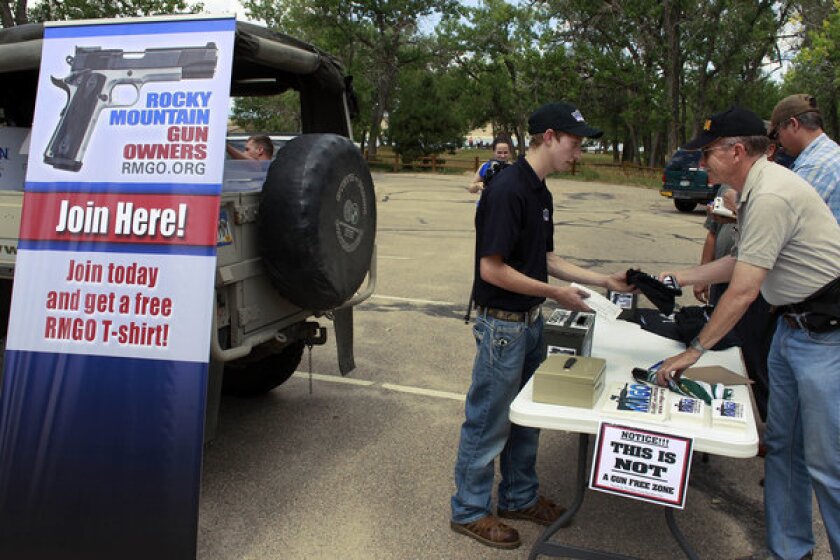 Seth Walters, a staffer for the gun rights group Rocky Mountain Gun Owners, hands out promotional T-shirts before a gun rights rally held Friday. Nearby, a Mayors Against Illegal Guns remembrance event was held honoring the victims of the Aurora theater shootings and advocating gun control.