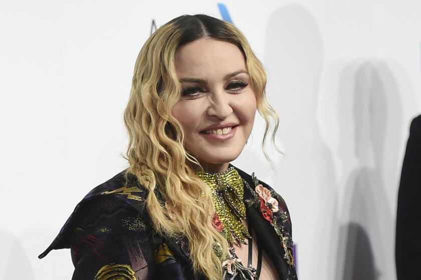 Madonna in a black embroidered dress smiling for cameras