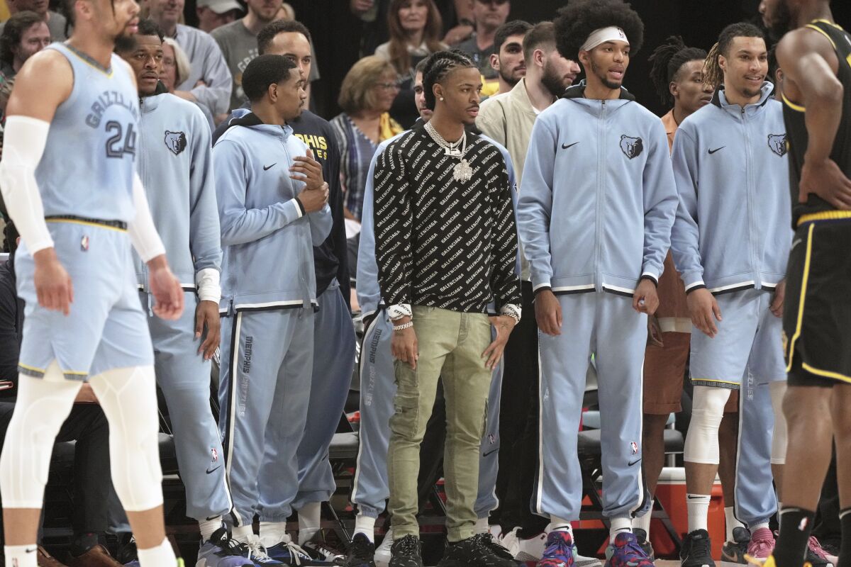 Memphis Grizzlies' Ja Morant, center, watches the game from the sidelines in the first half of Game 5 of an NBA basketball second-round playoff series against the Golden State Warriors Wednesday, May 11, 2022, in Memphis, Tenn. (AP Photo/Karen Pulfer Focht)