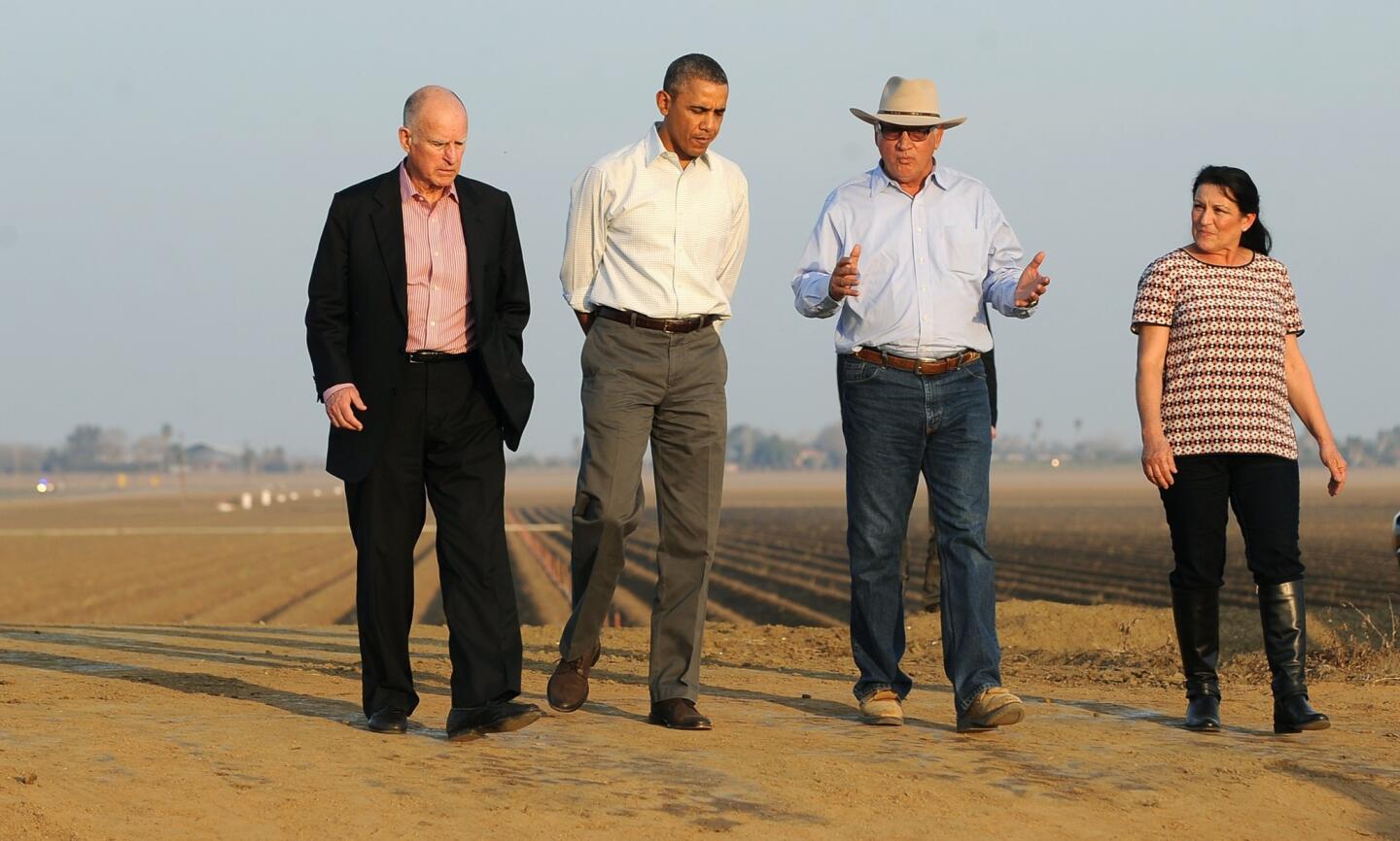 President Obama walks with Gov. Jerry Brown, left, and Joe and Maria Del Bosque on the Del Bosques' farm in Los Banos, Calif.