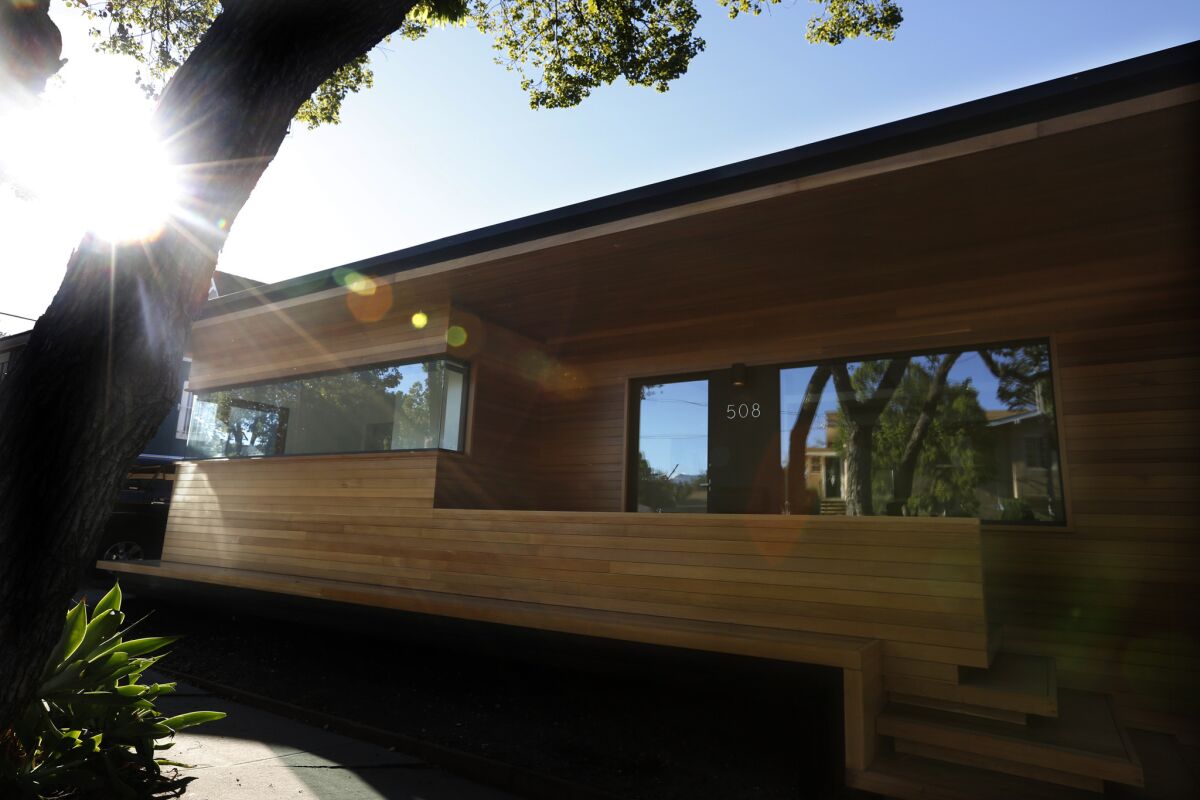 Today, the home features a dramatic new facade, which architect Martin Fenlon clad in clear cedar. Along the sidewalk facing the street, he also installed a long bench that was conceived to mirror the top of the house. The bench blurs the boundaries between public and private life as neighbors use it as a place to rest or play.