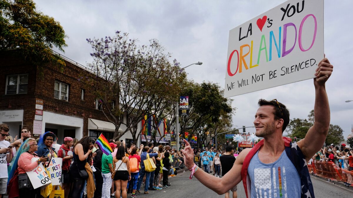 A participant in the gay pride parade Sunday in West Hollywood holds a sign expressing support for the Orlando shooting victims.