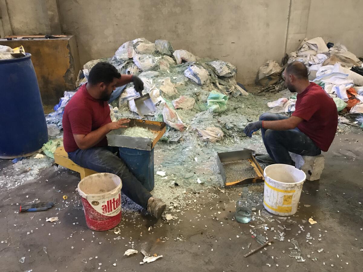 Workers at a factory in Lebanon sort through piles of shattered glass.