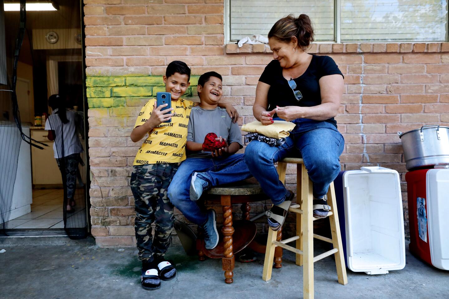 HOUSTON, TEXAS -- SATURDAY, OCTOBER 12, 2019: Dilcia Sabillon Aceituno, 40, of Naco, Honduras, with her twin sons Anthony Leiva Sabillon, 12, and Nostier Leiva Sabillon at her cousins apartment in Houston, Texas, on Oct. 12, 2019. Dilcia and Anthony were returned to Ciudad Juarez under "Remain in Mexico" while her husband and Nostier were allowed to stay in the U.S. in Houston. The three of them were recently united when Dilcia was allowed to pursue her amnesty case in the U.S. (Gary Coronado / Los Angeles Times)