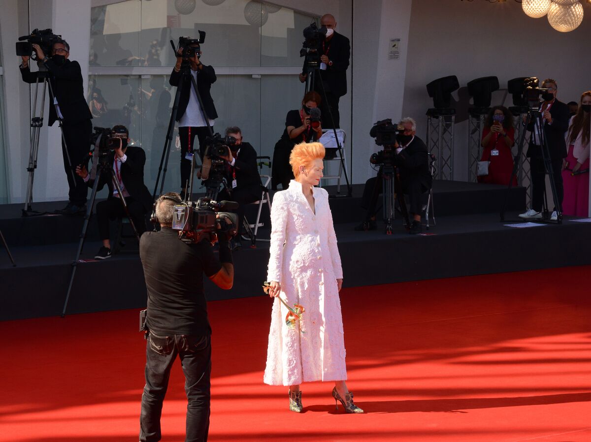 Actress Tilda Swinton holds a fanciful golden mask on the red carpet at the 77th Venice Film Festival.