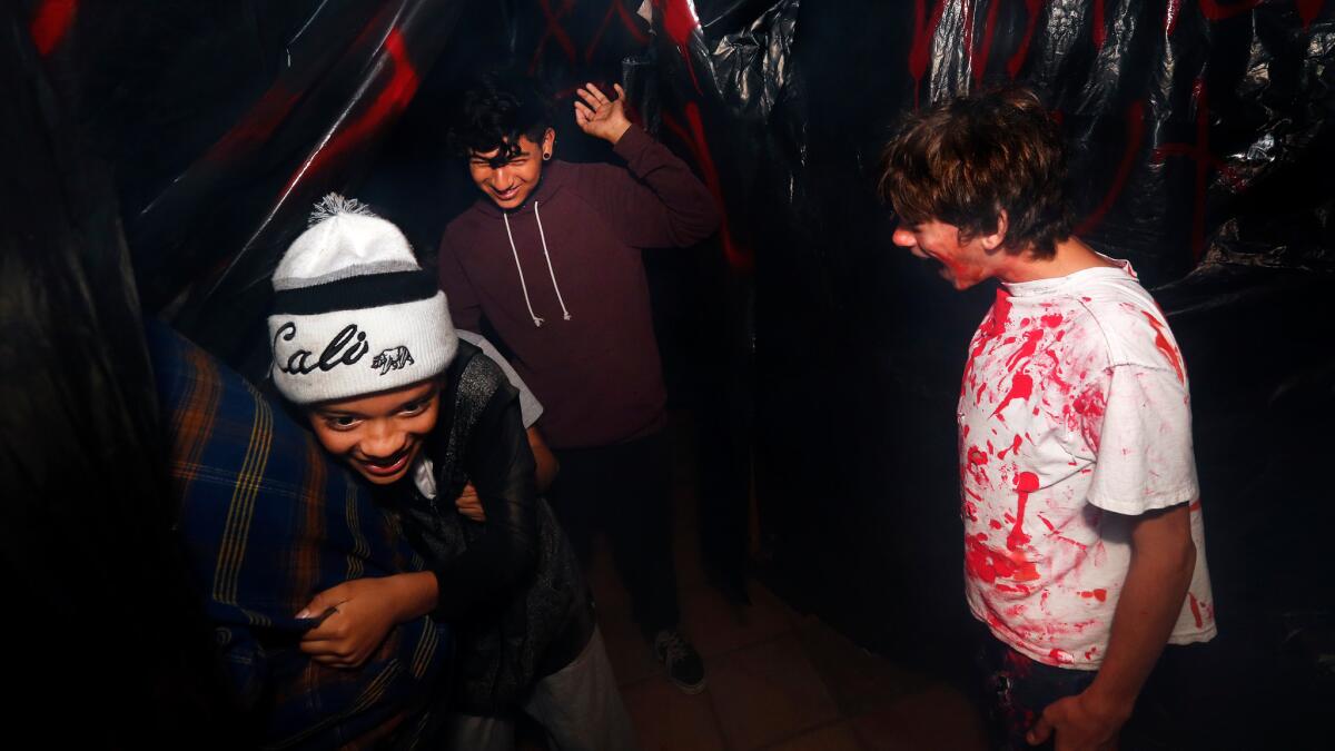 Oswaldo Corado, 12, left, and Carlos Zevallos, 16, are harassed by performer Sebastian Foster, 13, as they make their way through haunted maze.