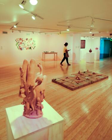 An art gallery with wooden floors displays ceramic works