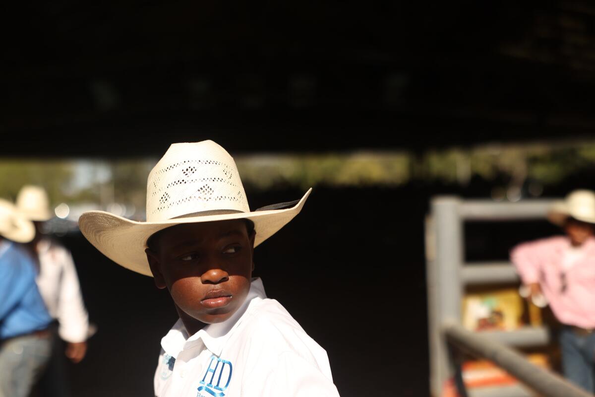 A boy in a cowboy hat stares into the distance.