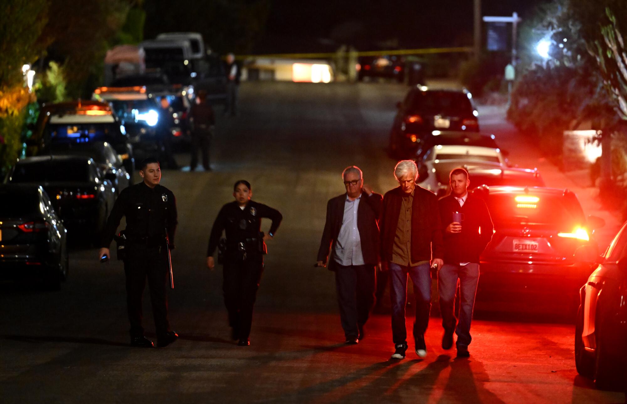 Keith Morrison, second from right, walks with police investigators down the street from Matthew Perry's house.