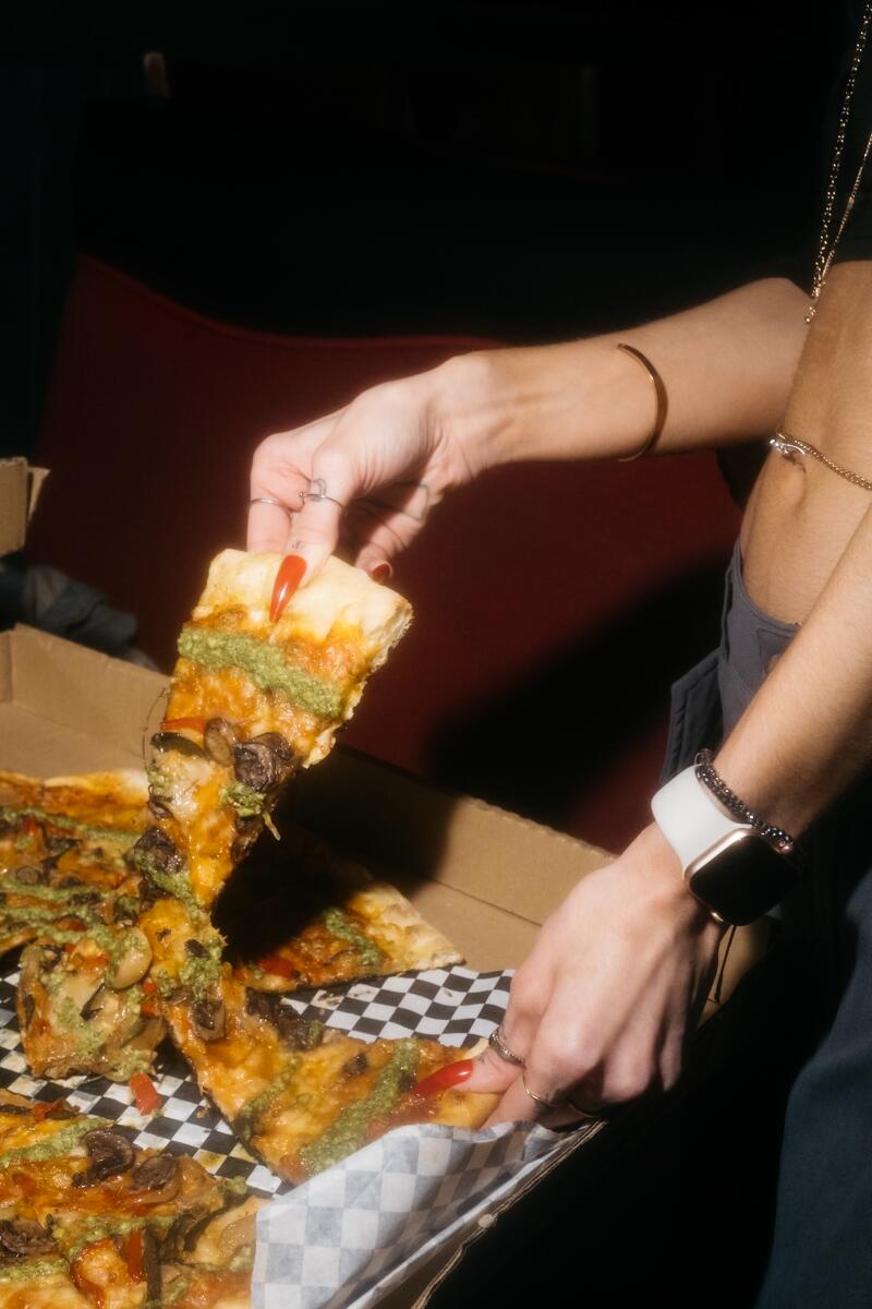 A woman enjoys a slice of pizza.