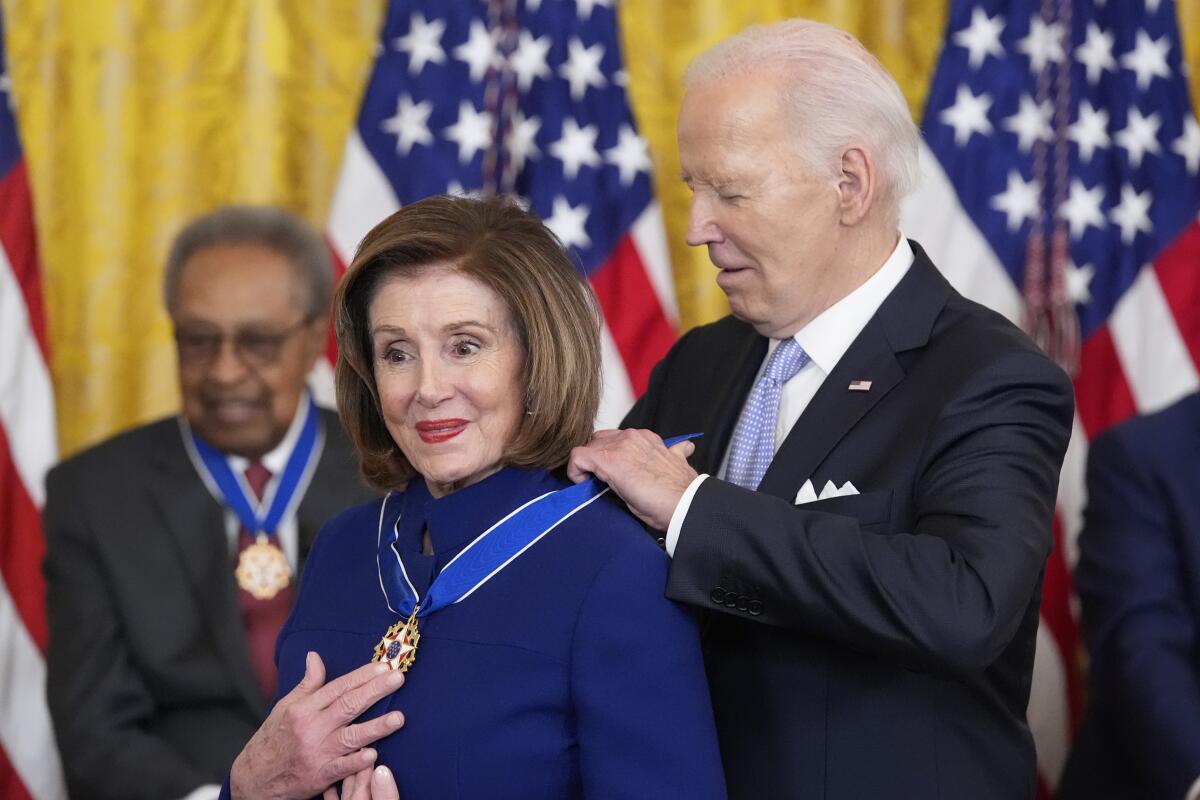 President Biden puts a medal around Rep. Nancy Pelosi's neck.