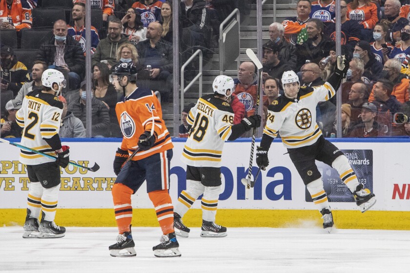 Boston Bruins' Craig Smith (12), Matt Grzelcyk (48) and Jake DeBrusk (74) celebrate a goal as Edmonton Oilers' Devin Shore (14) skates off during second-period NHL hockey game action in Edmonton, Alberta, Thursday, Dec. 9, 2021. (Amber Bracken/The Canadian Press via AP)