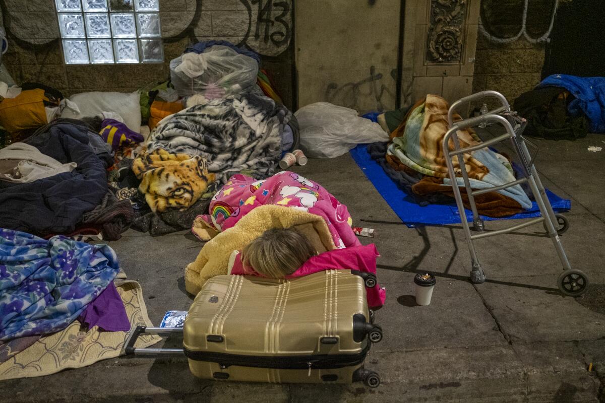 People sleep under blankets on dirty concrete
