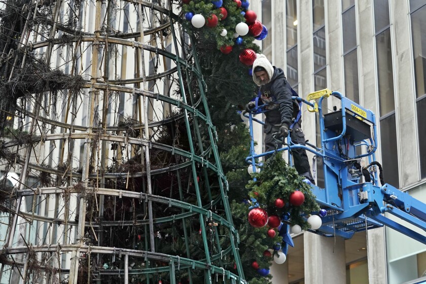 A worker disassembles a Christmas tree outside Fox News headquarters, in New York, Wednesday, Dec. 8, 2021. Police say a man is facing charges including arson for setting fire to a 50-foot Christmas tree in front of Fox News headquarters in midtown Manhattan. The tree outside of the News Corp. building that houses Fox News, The Wall Street Journal and the New York Post caught fire shortly after midnight Wednesday. (AP Photo/Richard Drew)