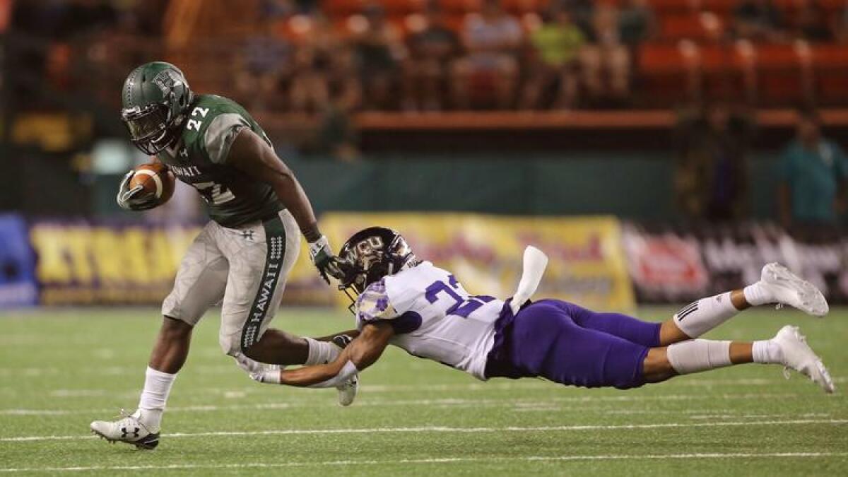 Hawaii running back Diocemy Saint Juste tries to get past Western Carolina defensive back JerMichael White on Sept. 2.