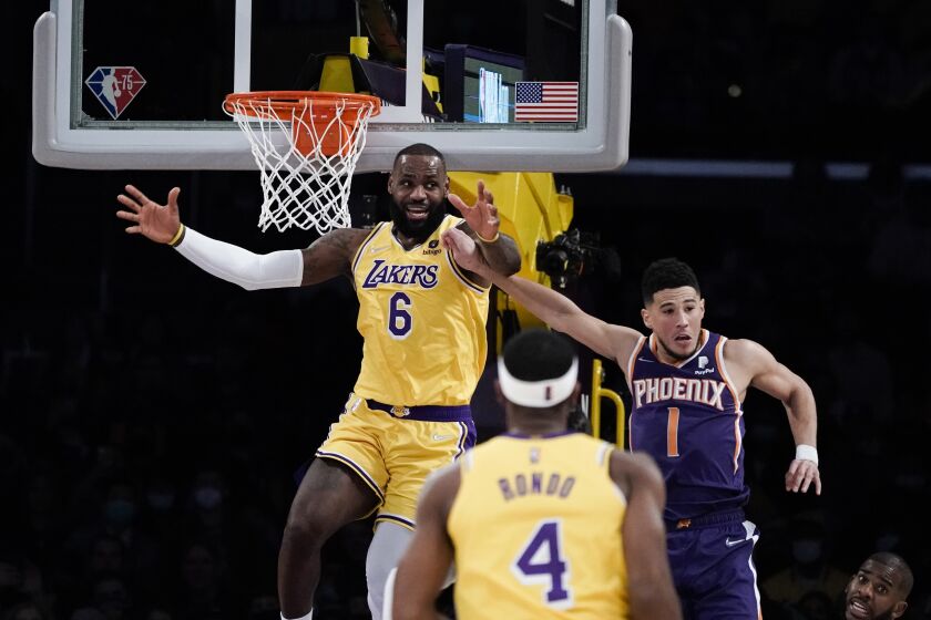 Los Angeles Lakers' LeBron James, left, reacts after missing a basket under pressure from Phoenix Suns' Devin Booker during first half of an NBA basketball game Tuesday, Dec. 21, 2021, in Los Angeles. (AP Photo/Jae C. Hong)