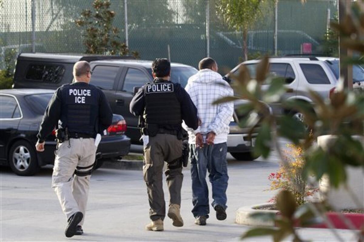 In this March 30, 2012 photo, Immigration and Customs Enforcement (ICE) agents take a suspect into custody as part of a nationwide immigration sweep in Chula Vista, Calif.