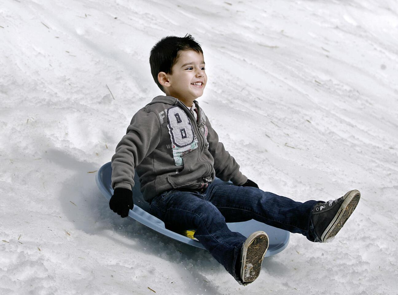 Alec Yeghikian, 3 of Glendale, grins from ear to ear as he slides all the way down a man-made snowbank during the St. Mary's Armenian Church Annual Winter Wonderland at the church's parking lot in Glendale on Saturday, January 26, 2013. The event was sponsored by the Armenian Relief Society of Western USA.