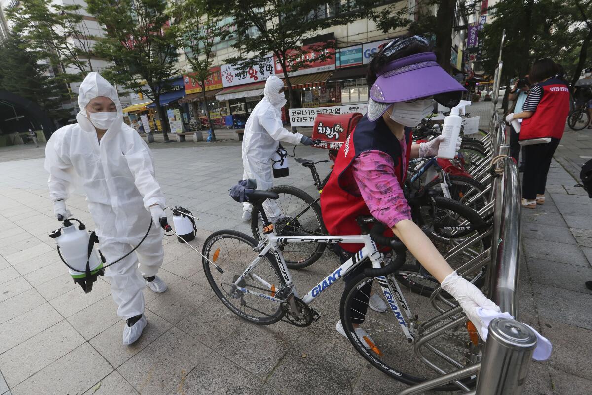 Trabajadores y voluntarios desinfectan bicicletas contra el coronavirus en una calle en Goyang, Corea del Sur