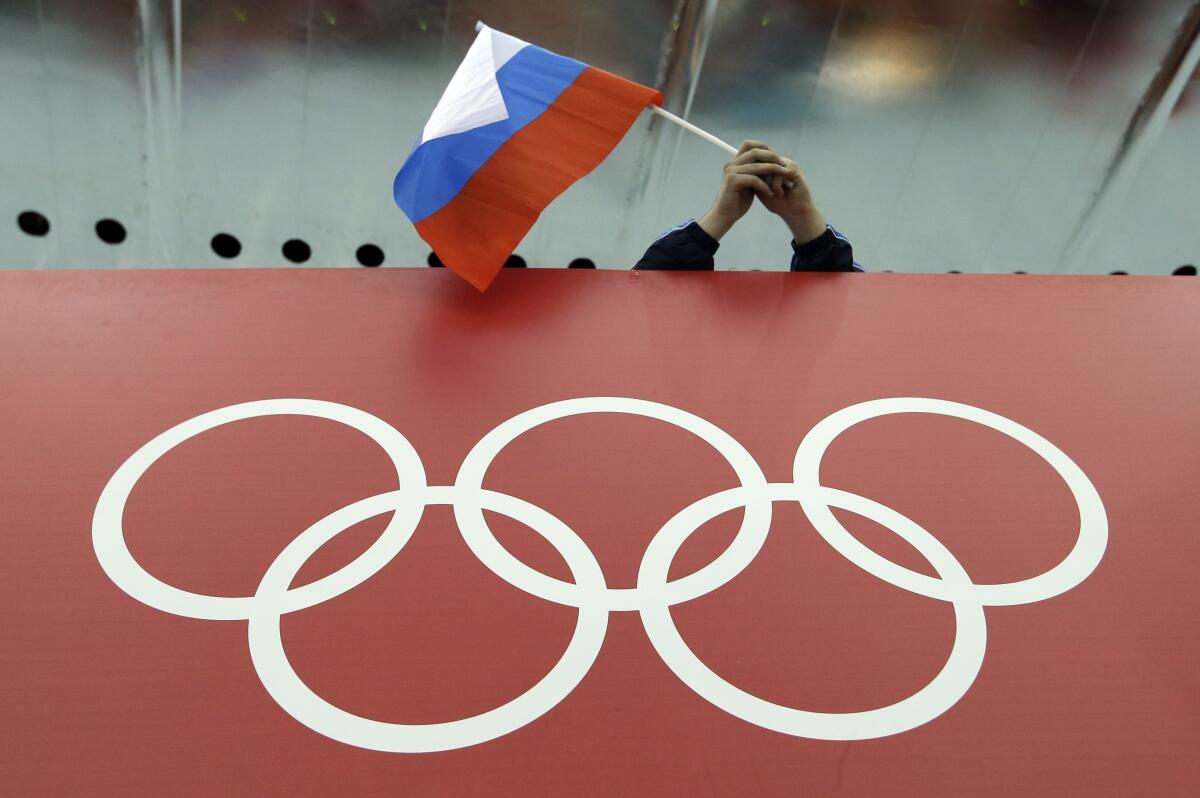 A Russian flag is held above the Olympic Rings at Adler Arena Skating Center during the Winter Olympics in Sochi, Russia.  