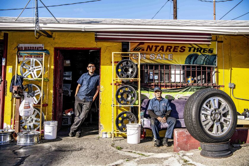 LOS ANGELES, CA - MARCH 26: Luis Moreno, left, and Author Bernal, both employees at Flaco's Tires on Thursday, March 26, 2020 in Los Angeles, CA. Moreno, who lives with his girlfriend and their 5 year old son, agreed to a pay reduction as business has been hit hard by the coronavirus pandemic. "We normally do at least fifteen cars a day" said Moreno, "Now, it's maybe four". (Mariah Tauger / Los Angeles Times)