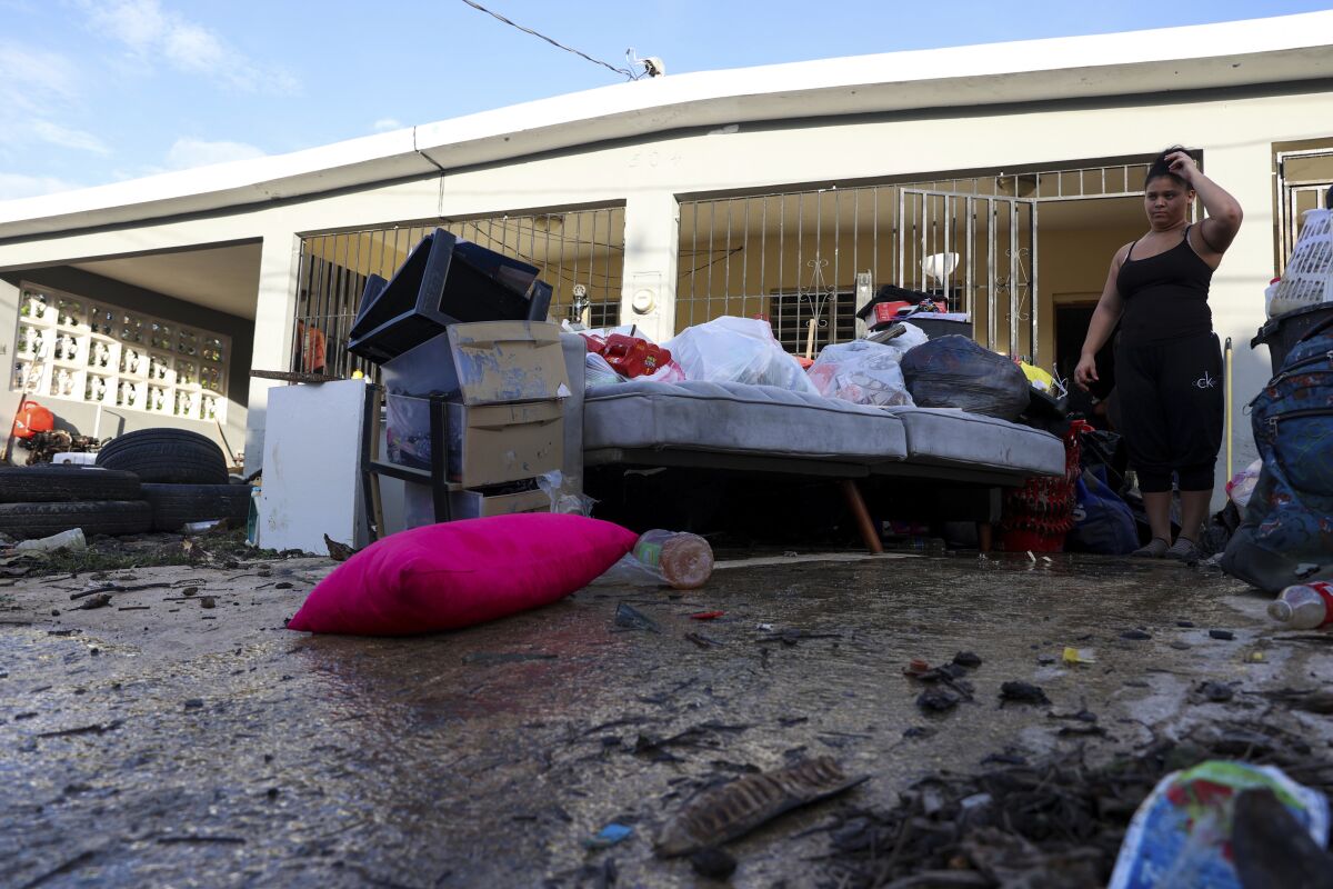 A woman looks at her water-damaged belongings outside her home.