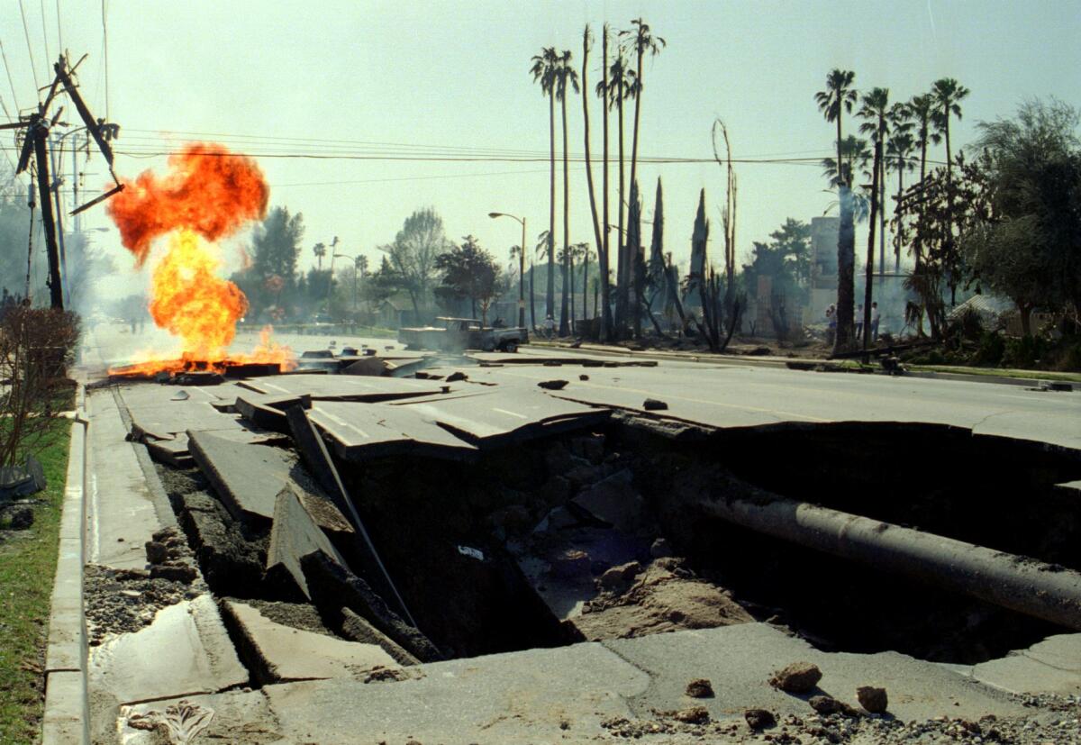 A ruptured gas main burns behind a giant crater on Balboa Boulevard in Granada Hills in 1994.