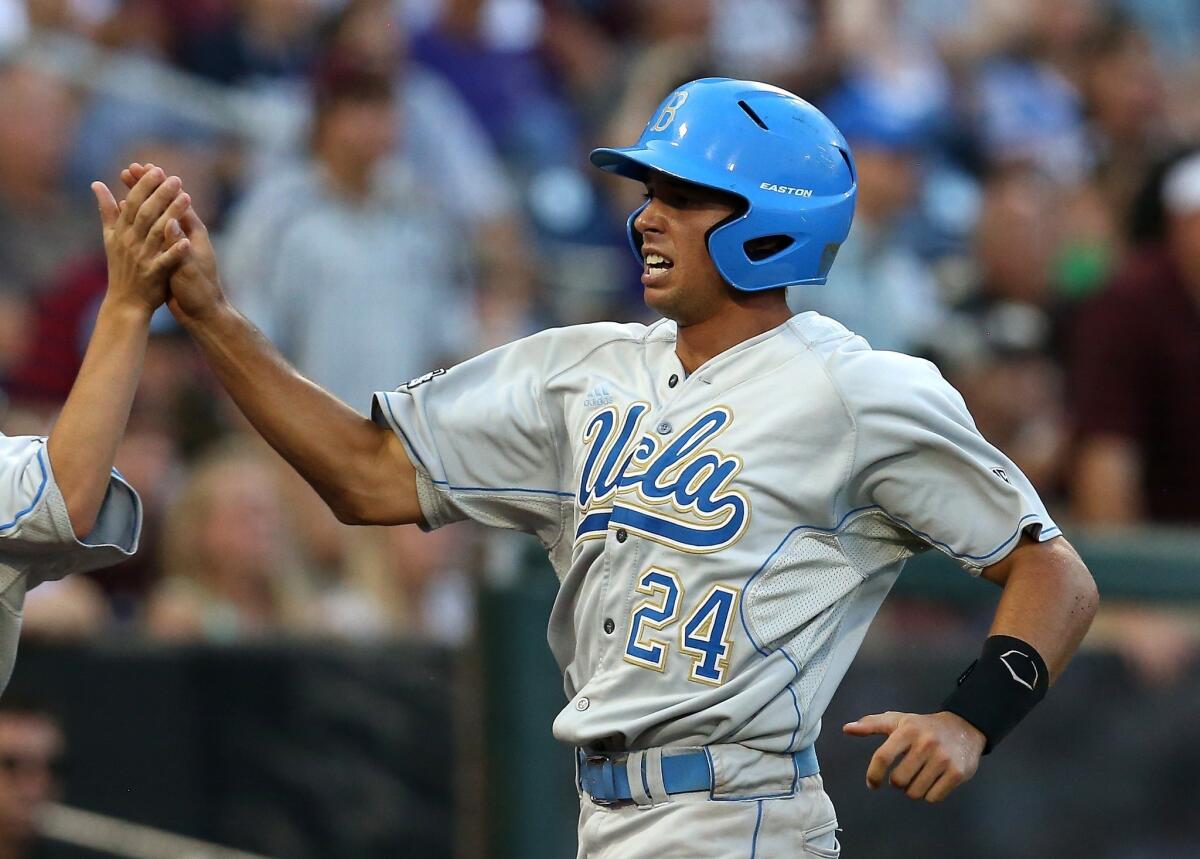 UCLA's Brian Carroll is congratulated after scoring a run during the Bruins' victory over Mississippi State at the College World Series on Monday.