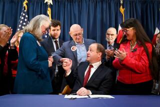 DENVER, CO - APRIL 28 : Gov. Jared Polis signed four gun control bills and hands the pen to Sandy and Lonnie Phillips, parents of Aurora theater shooting victim Jessica Ghawi, at the governor's office in Colorado State Capitol Building in Denver, Colorado on Friday, April 28, 2023. (Photo by Hyoung Chang/The Denver Post)