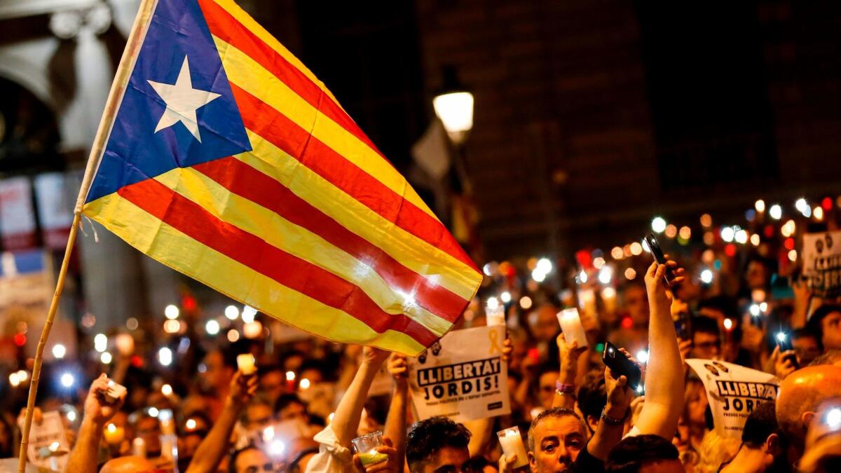People hold candles and a Catalan pro-independence "Estelada" flag during a demonstration in Barcelona against the arrest of two separatist leaders on Oct. 17.