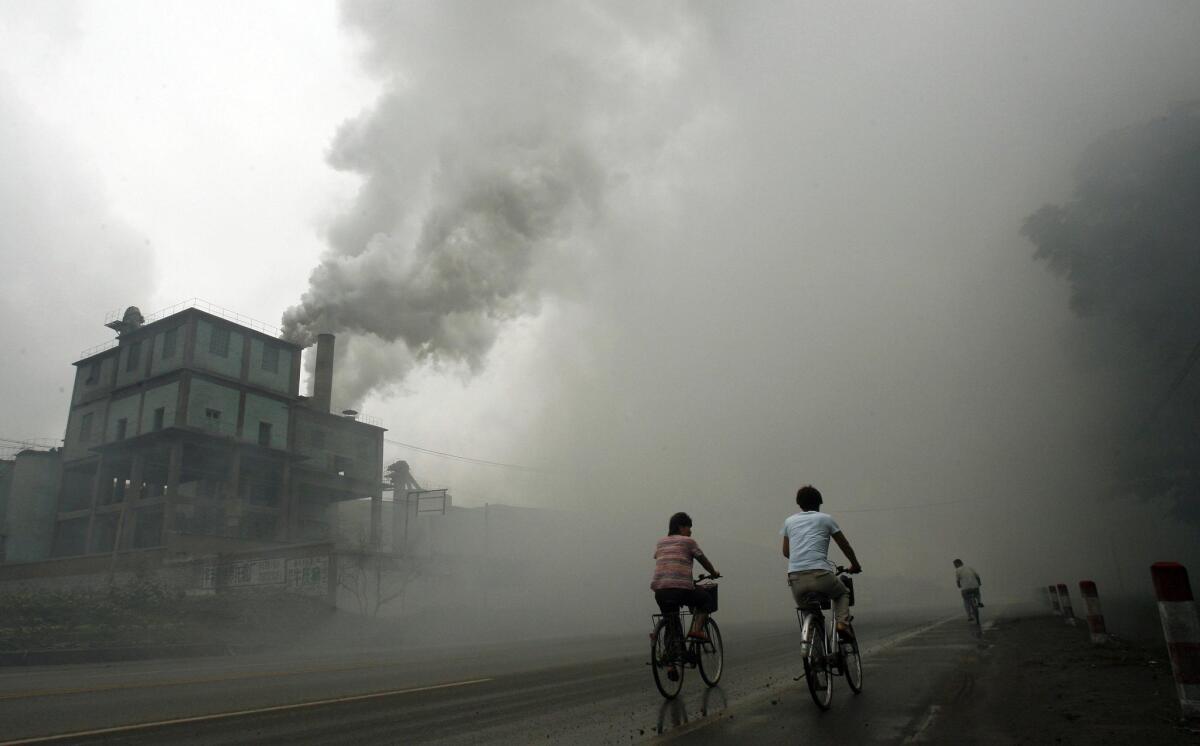 Cyclists pass through thick pollution in 2006 from a factory in Yutian, east of Beijing.