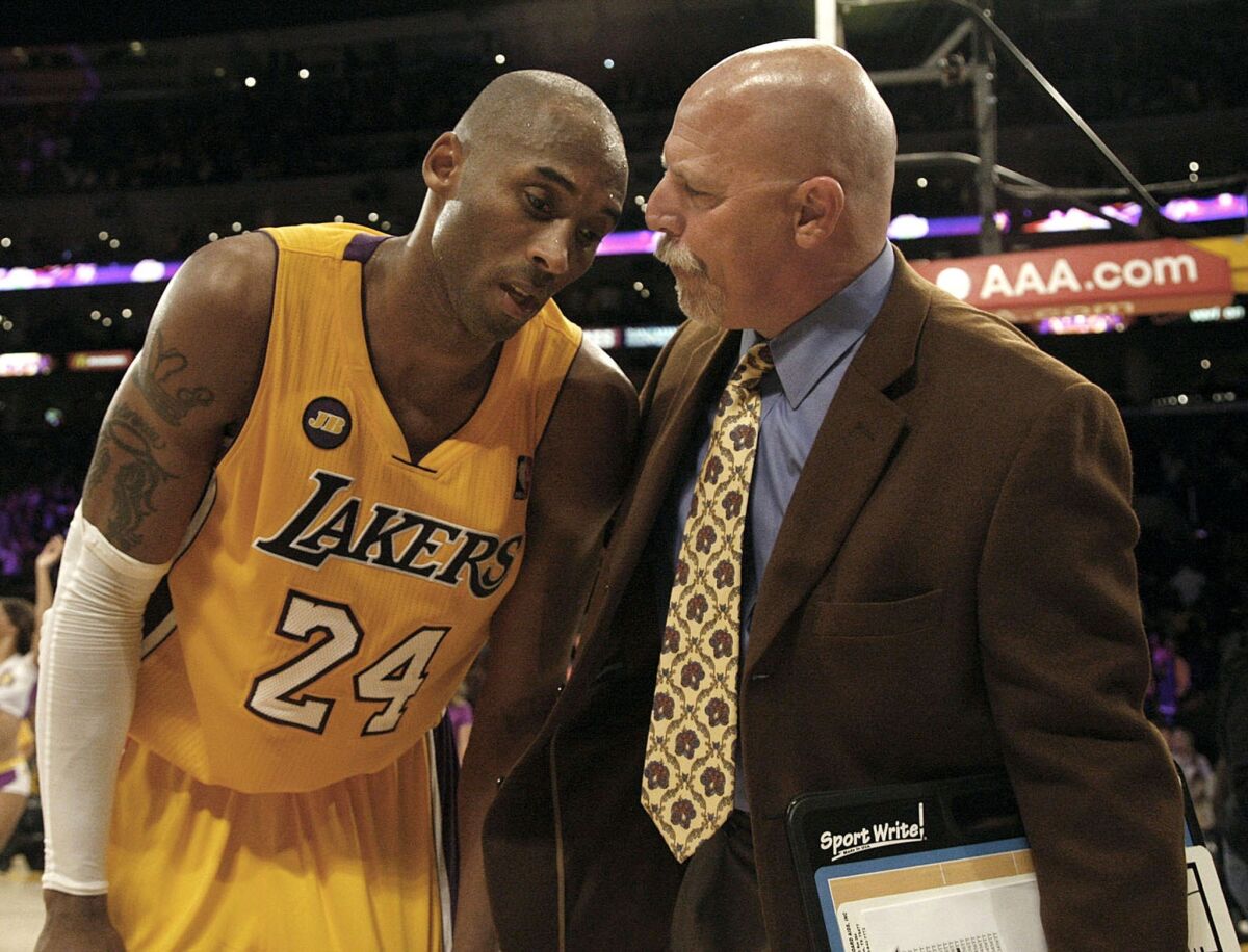 Lakers trainer Gary Vitti checks on a winded Kobe Bryant in a game in March.