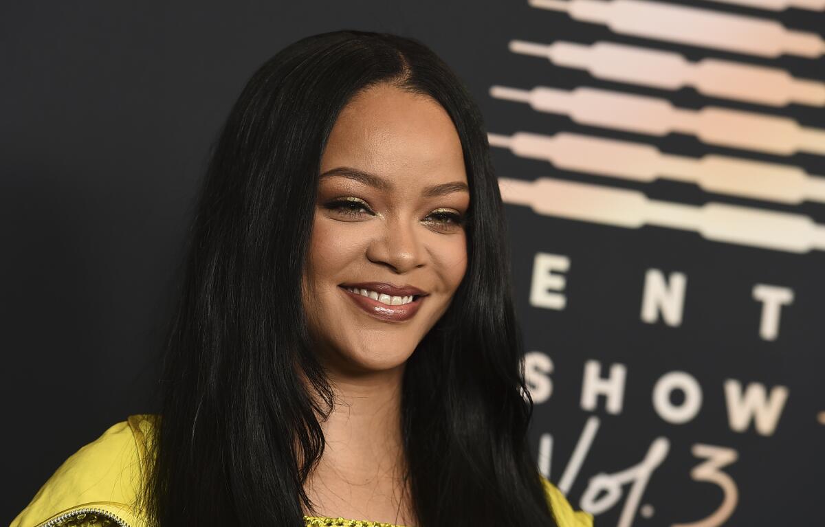 A woman with long black hair smiling in a yellow outfit