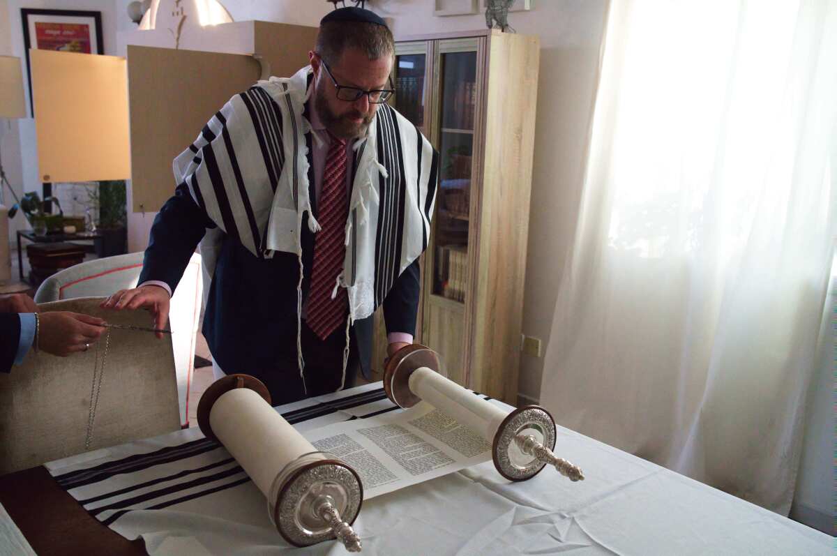 A cantor prepares to read from a Torah scroll in Dubai, United Arab Emirates