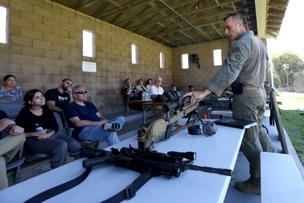 Members of the Glendale Police Advisory Panel listen to Mike Woolner, a sniper with the Glendale Police Department's SWAT team, talk about the different equipment he uses in the field during a special training day at the department's outdoor firing range on Saturday.