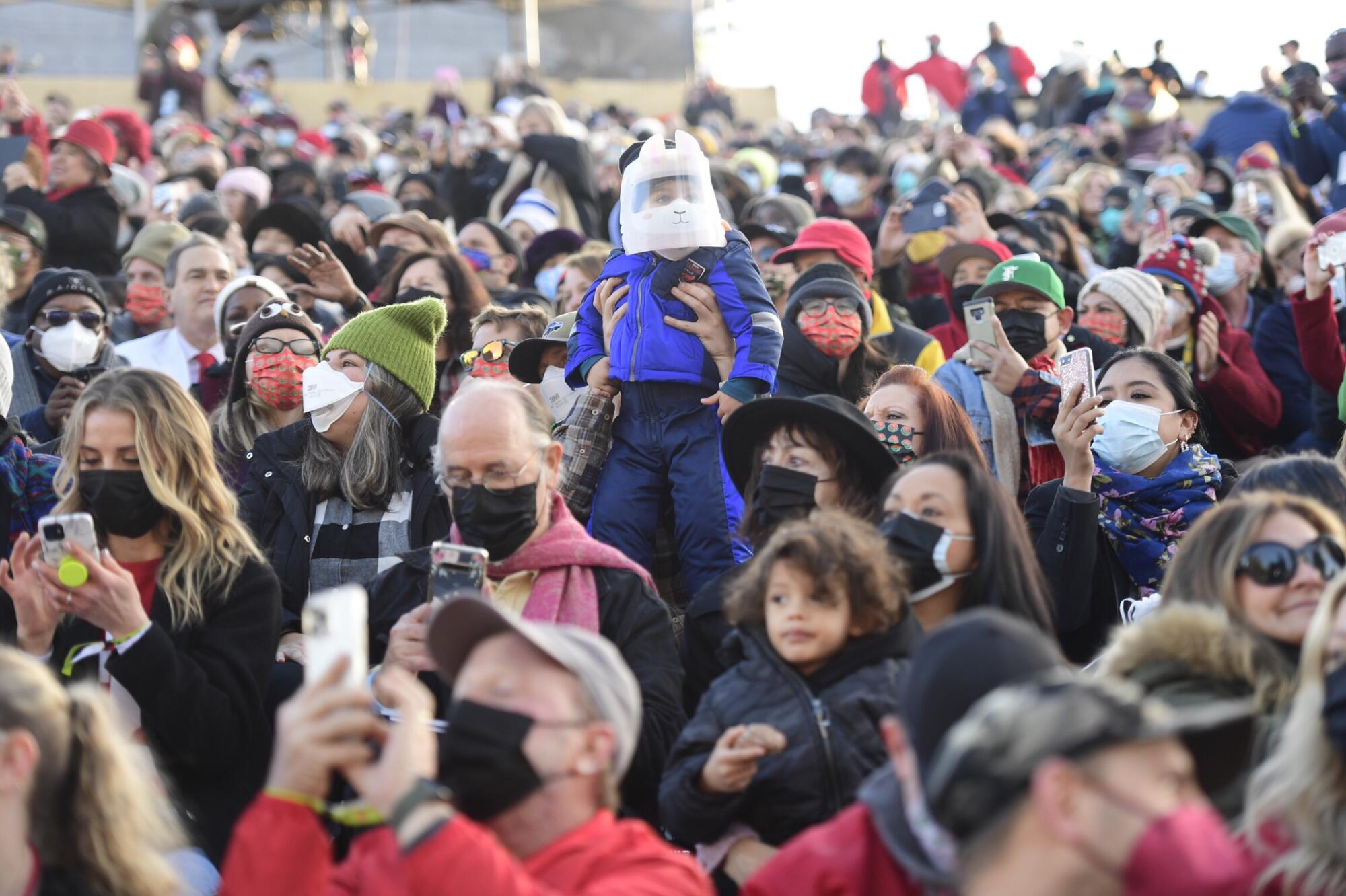 The crowd watches the parade and takes pictures.