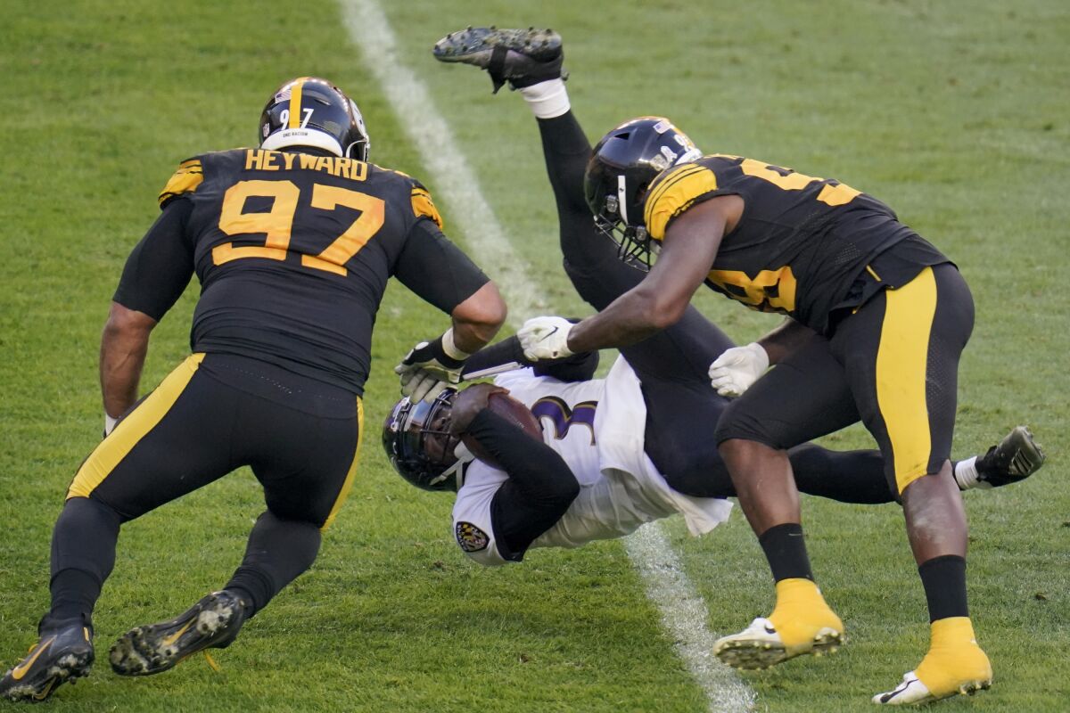 Baltimore Ravens quarterback Robert Griffin III (3) flies as he is tripped up as he scrambles past Pittsburgh Steelers defensive end Cameron Heyward (97) and inside linebacker Vince Williams (98) in the first half during an NFL football game, Wednesday, Dec. 2, 2020, in Pittsburgh. (AP Photo/Gene J. Puskar)