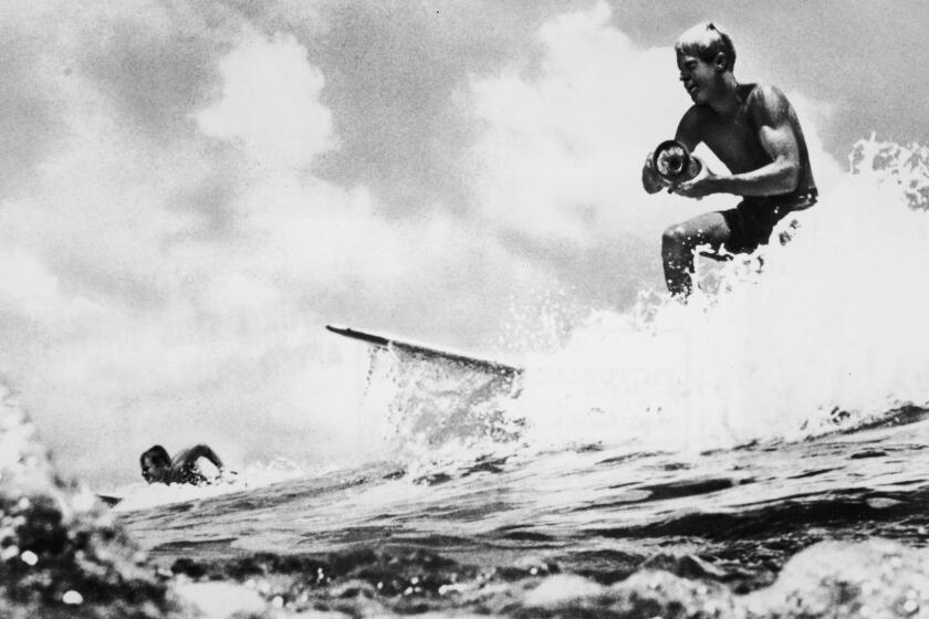 American surfer and director Bruce Brown surfs a wave and holds a camera while filming footage for his international surfing documentary, 'The Endless Summer,' circa 1966. Another surfer rides in the background. (Photo by Pictorial Parade/Getty Images) ** OUTS - ELSENT, FPG, CM - OUTS * NM, PH, VA if sourced by CT, LA or MoD **