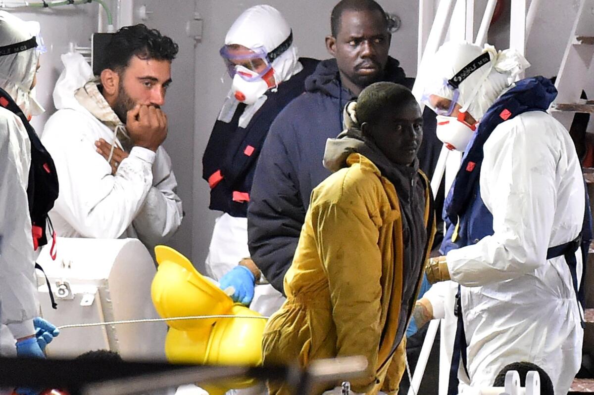 Mohammed Ali Malek, left, stands on the deck of the Italian Coast Guard ship Gregretti.