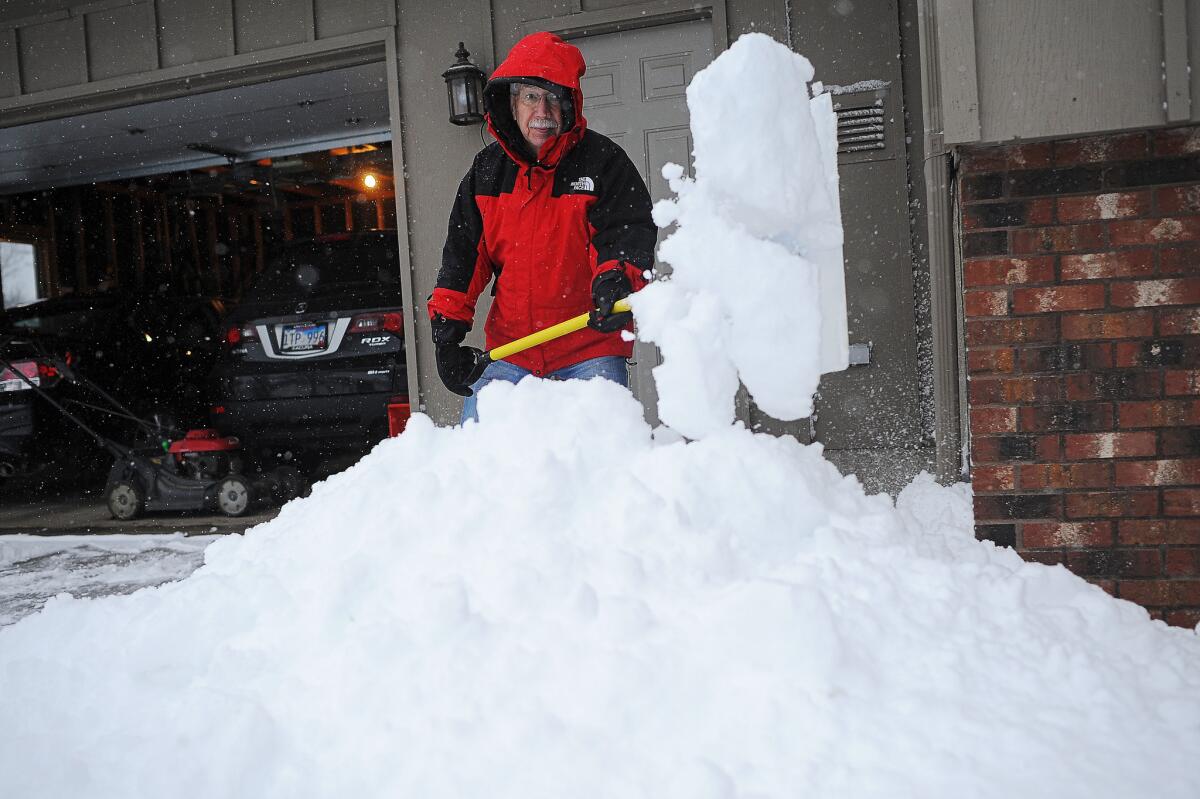 Jim Paulson, de Sioux Falls, retira nieve de su entrada con una pala antes de utilizar una máquina para quitar lo demás durante la primera nevada de la temporada.
