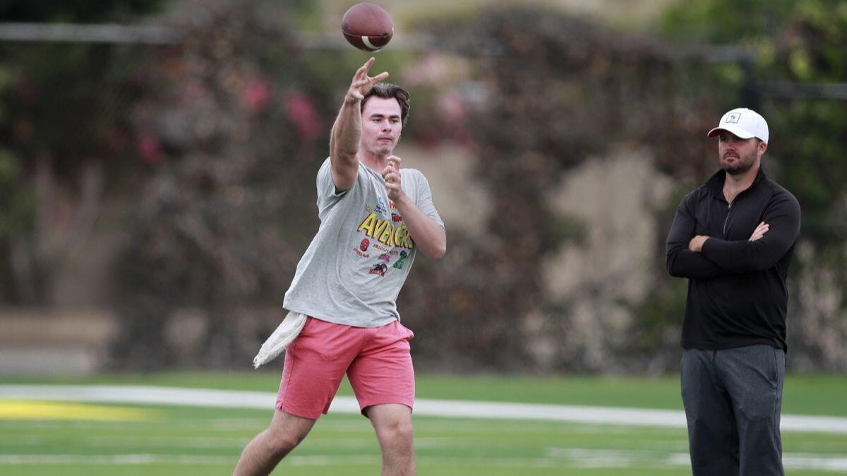 USC quarterback coach Adam Dedeaux, right, watches incoming USC freshman quarterback J.T. Daniels passes to his teammate, wide receiver Amon-Ra St. Brown at Golden West College in Huntington Beach on May 30.