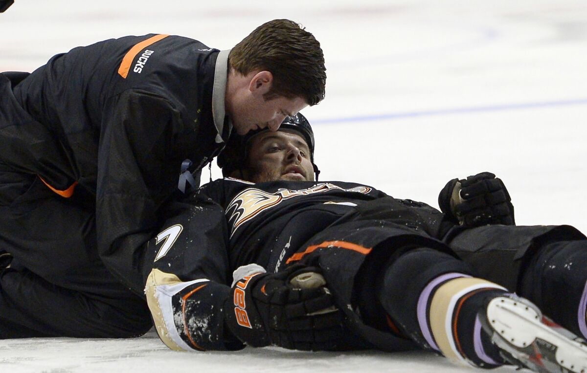 A Ducks team trainer assists left wing Dustin Penner after he was briefly knocked unconscious on a hit by Dallas Stars forward Ryan Garbutt during Sunday's game.