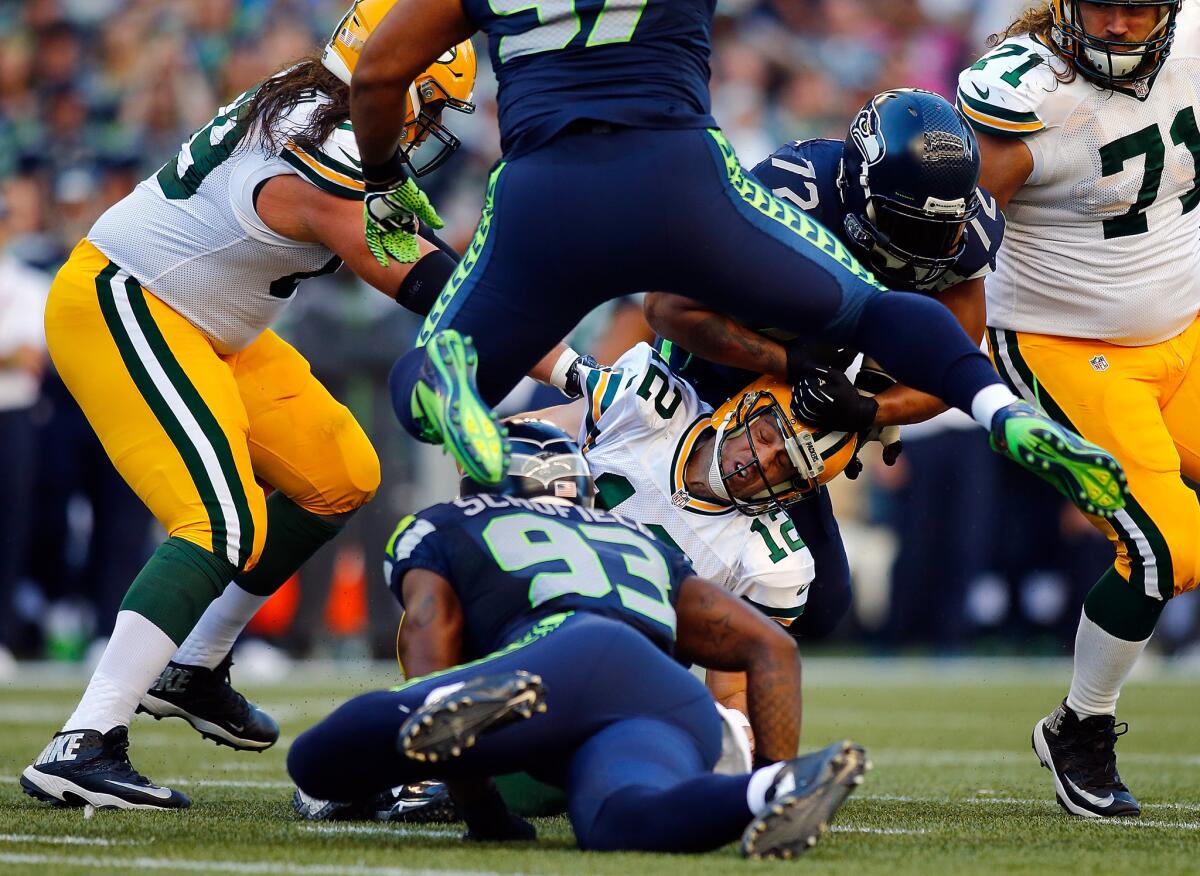 Green Bay quarterback Aaron Rodgers is tackled by defensive end O'Brien Schofield of the Seattle Seahawks during first game of the NFL season.