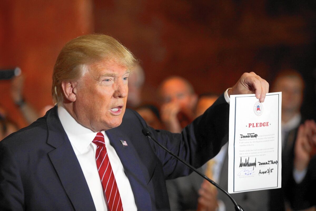 Donald Trump holds up a pledge -- dated Aug. 3. He later tweeted a document with the correct date.