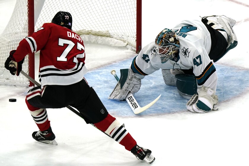 San Jose Sharks goaltender James Reimer, right, makes a save on a shot by Chicago Blackhawks center Kirby Dach during the first period of an NHL hockey game in Chicago, Sunday, Nov. 28, 2021. (AP Photo/Nam Y. Huh)