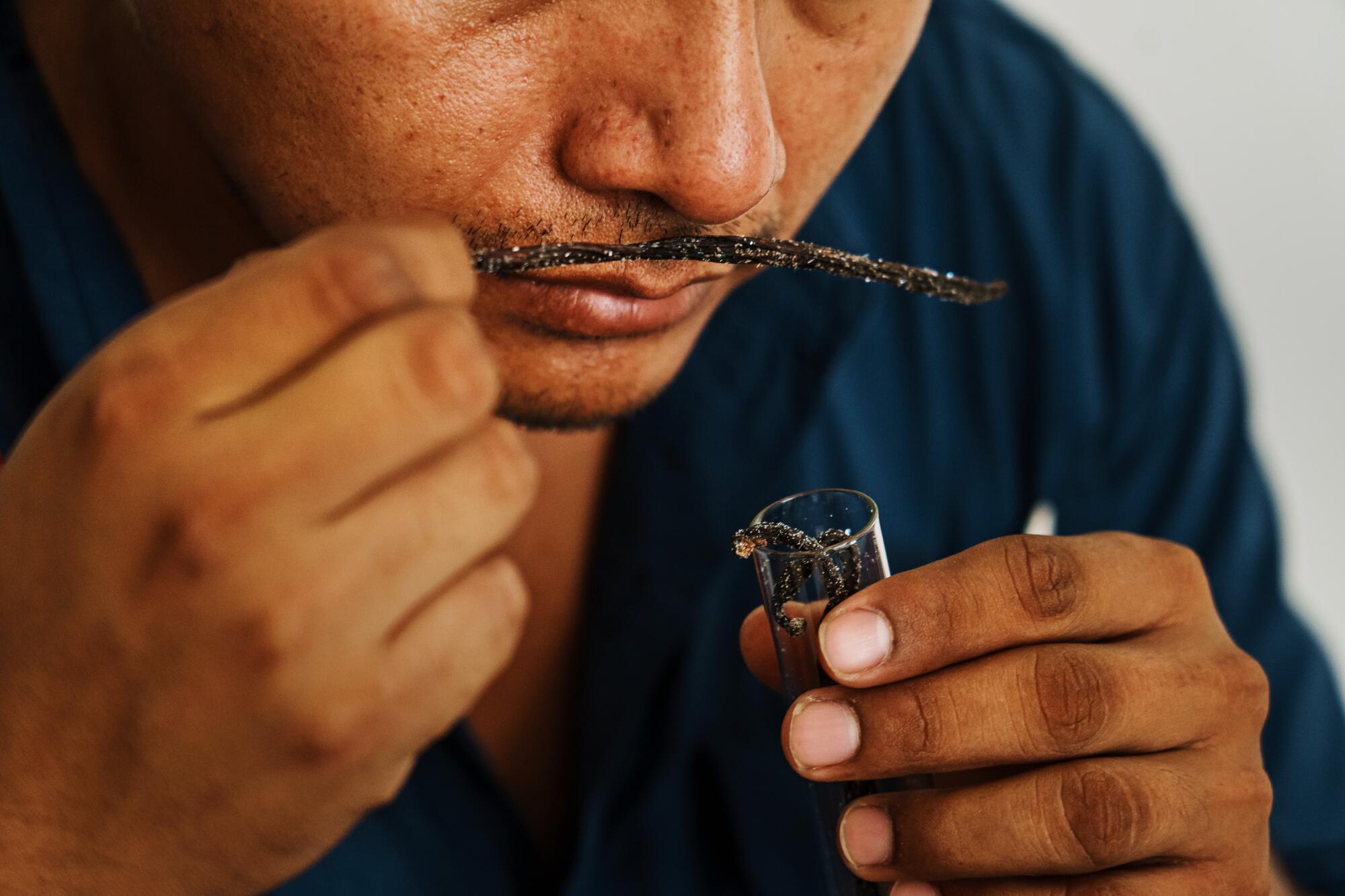 A man holds a vanilla bean to his nose